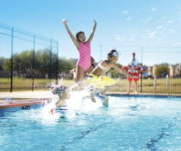 Kids splashing into the outdoor pool having a blast
