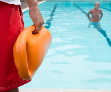 Lifeguard on pool deck keeping swimmers safe