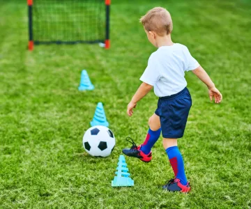 Little Boy practicing soccer outdoors