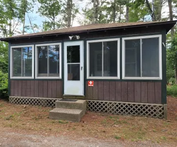 Camp Yomechas Nurses Cabin - Brown building with lots of windows and red nurse sign